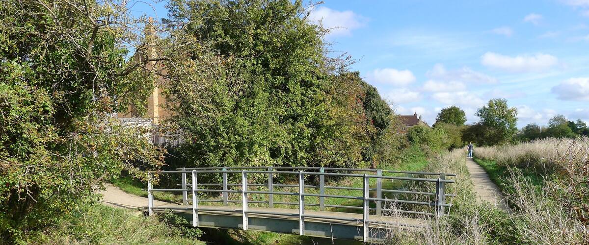 A narrow waterway with a pedestrian bridge crossing over it.