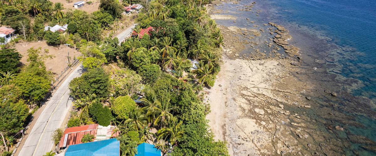 A coastal landscape with a beach, rocky shoreline, and lush greenery.