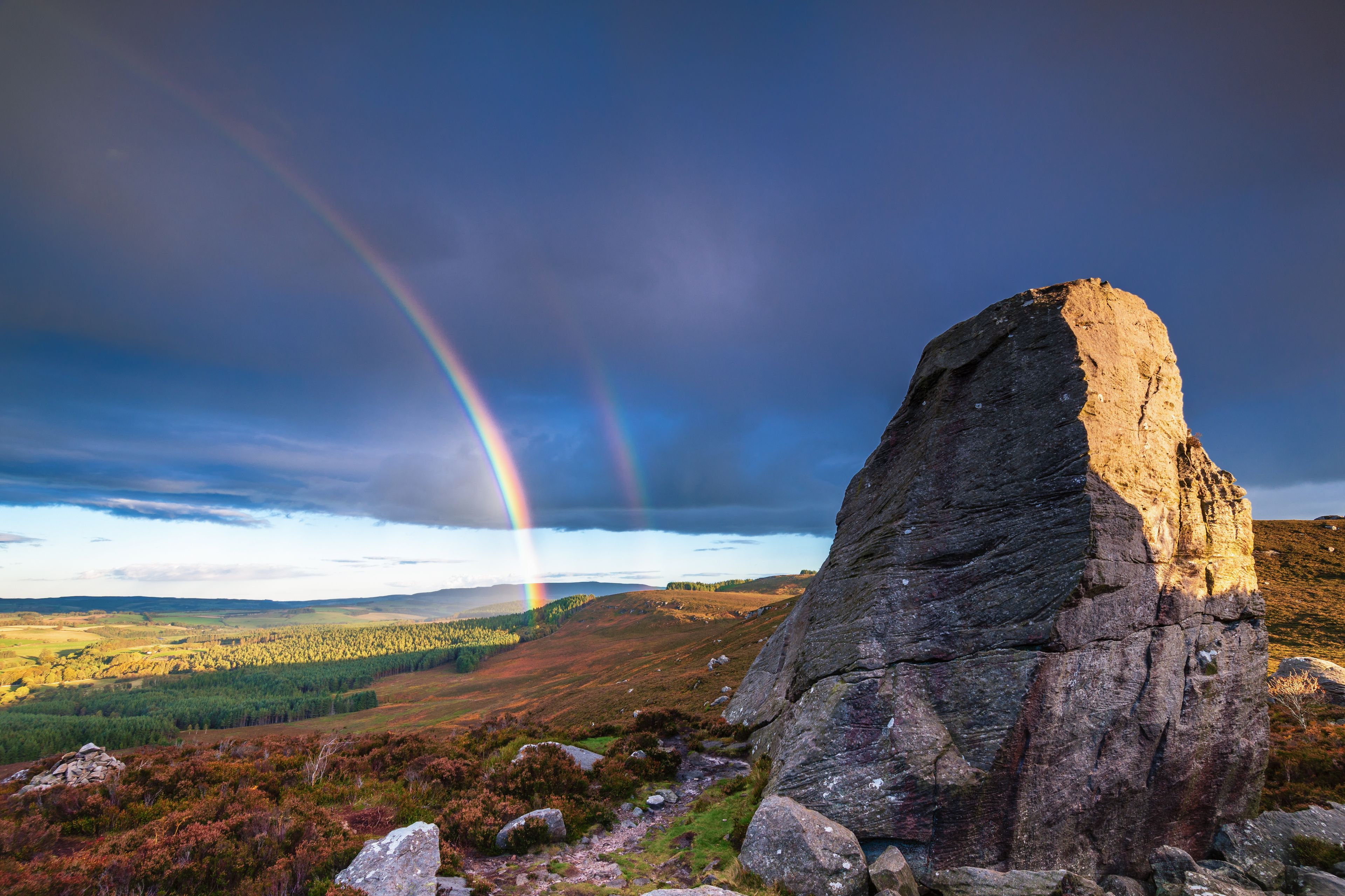 A rock formation with a rainbow in the background.