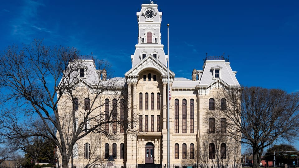A large, historic building with a clock tower, arched windows, and a prominent entrance.