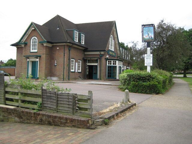A traditional brick building with a green door and windows, a signboard, and a paved entrance area.