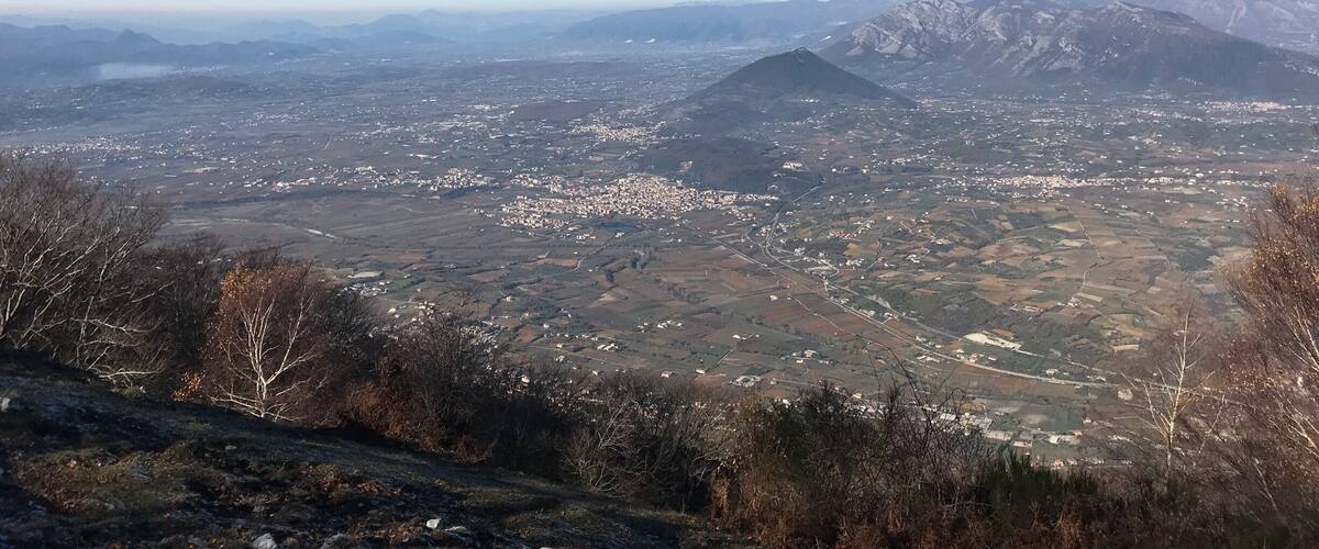 A panoramic view of a valley with mountains in the background and a clear blue sky.