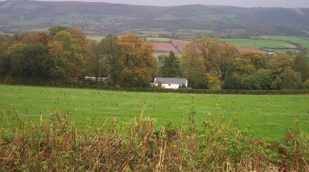 Hartrow Manor. Lying in the valley between the Quantocks and the Brendon Hills, the house is well sheltered by mature trees. The photograph is taken from the B3224 looking north east with the Quantocks in the background.