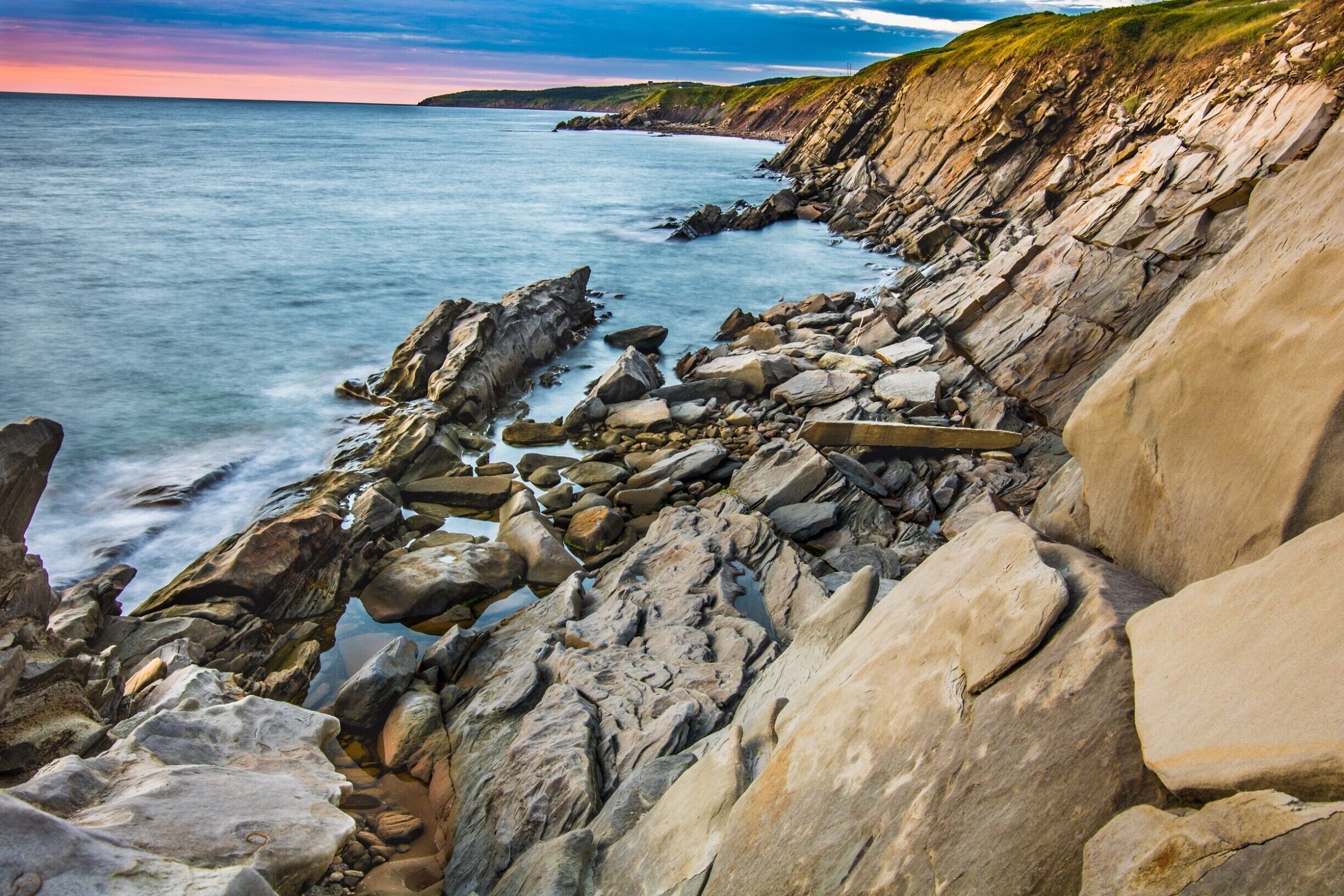 A rocky coastline with large boulders and waves crashing against the shore.