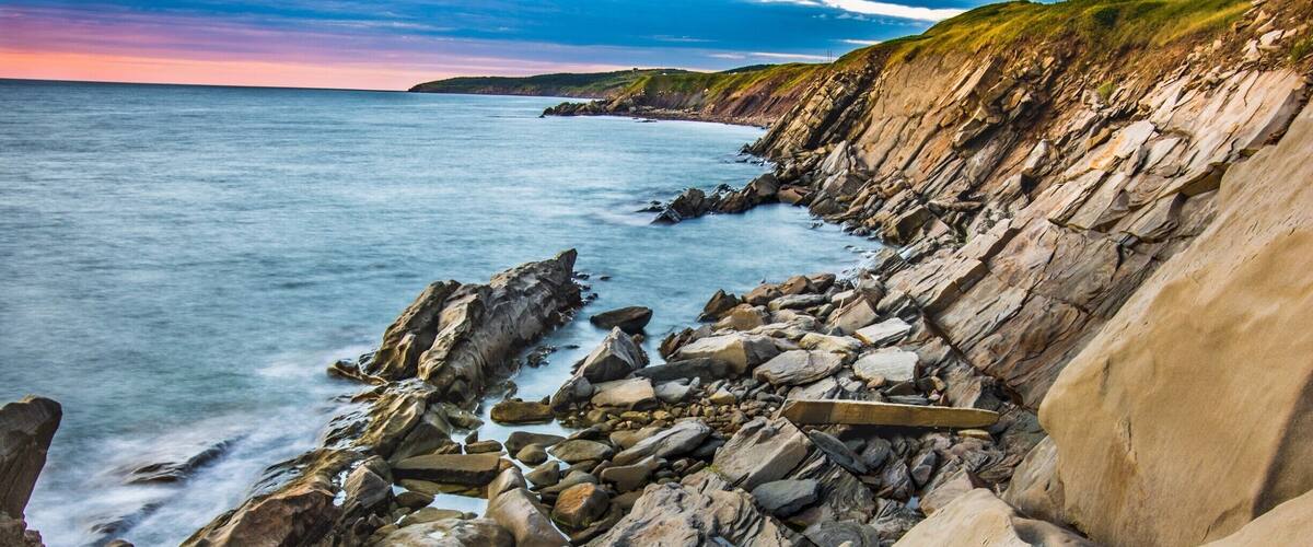 A rocky coastline with large boulders and waves crashing against the shore.