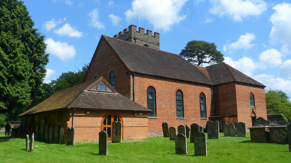 A church with a bell tower, a small adjacent building, and a cemetery with headstones.