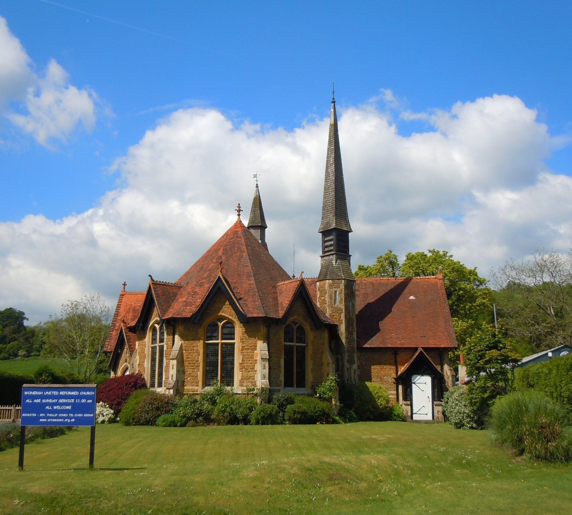 A church with a tall steeple and a red-tiled roof.