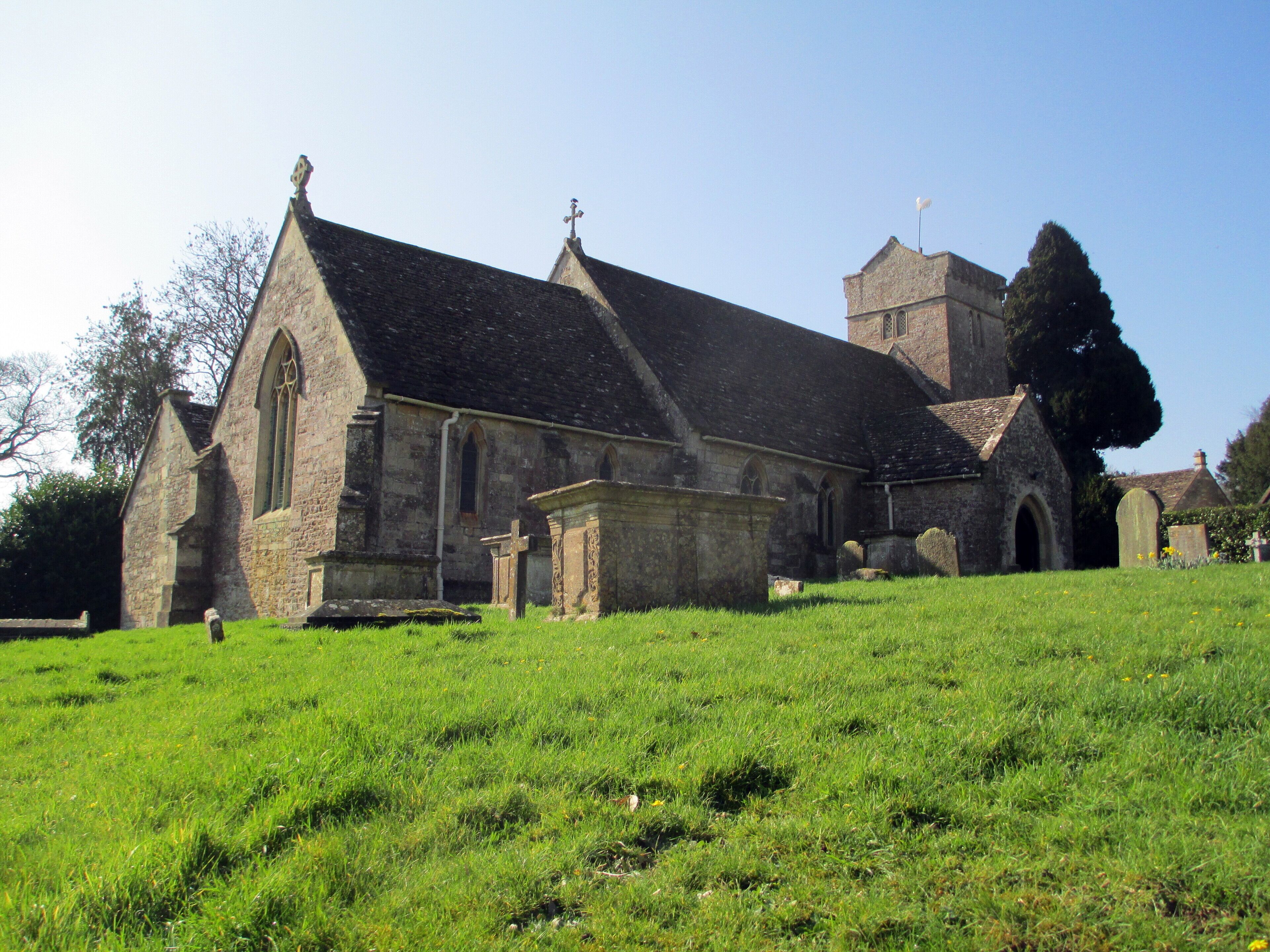 A church with a tall tower and a grassy field in front.