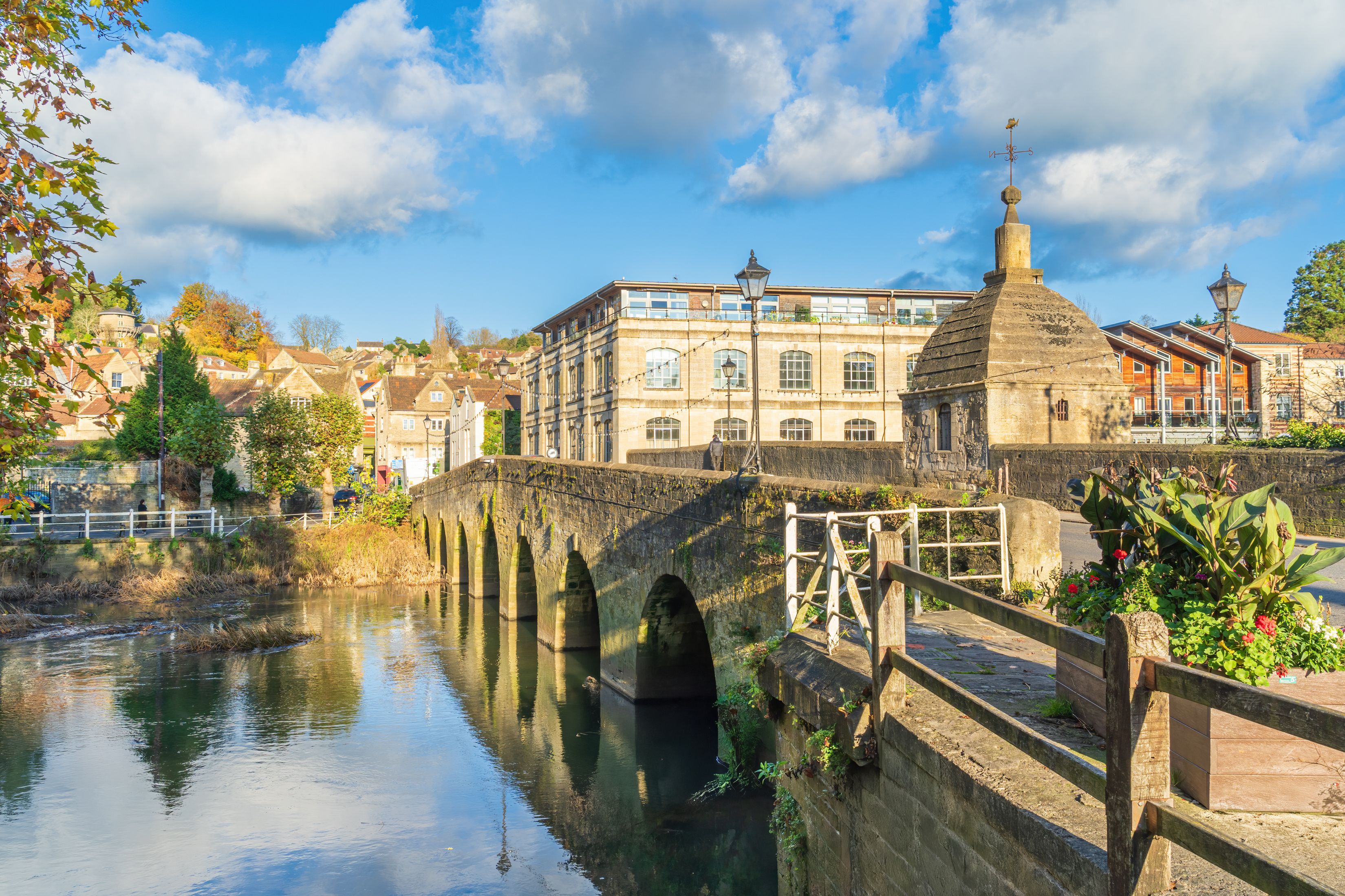 A stone bridge over a river, historic buildings, and a clear blue sky.