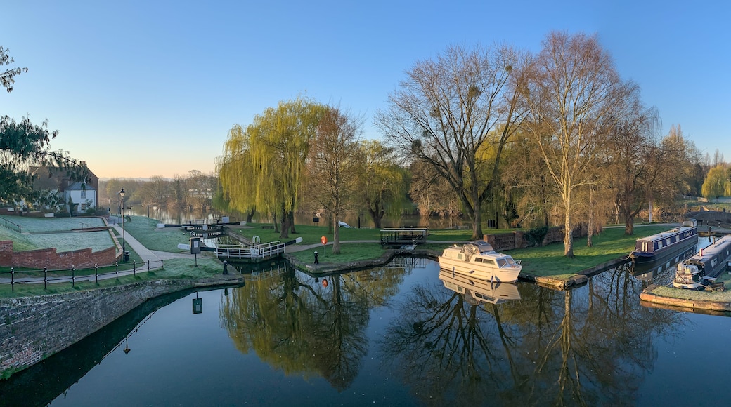 Ein Kanal mit Booten, einer Brücke und Bäumen, deren Spiegelung sich im Wasser zeigt.