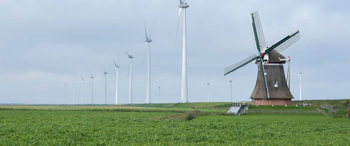 A windmill and wind turbines in a field.