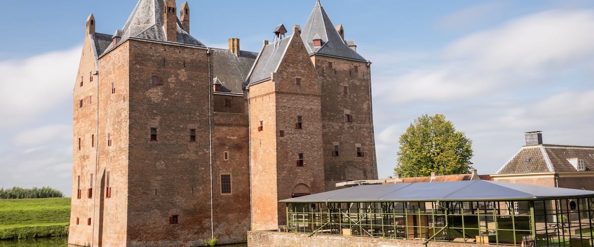 A large brick castle with multiple towers and a glass conservatory.