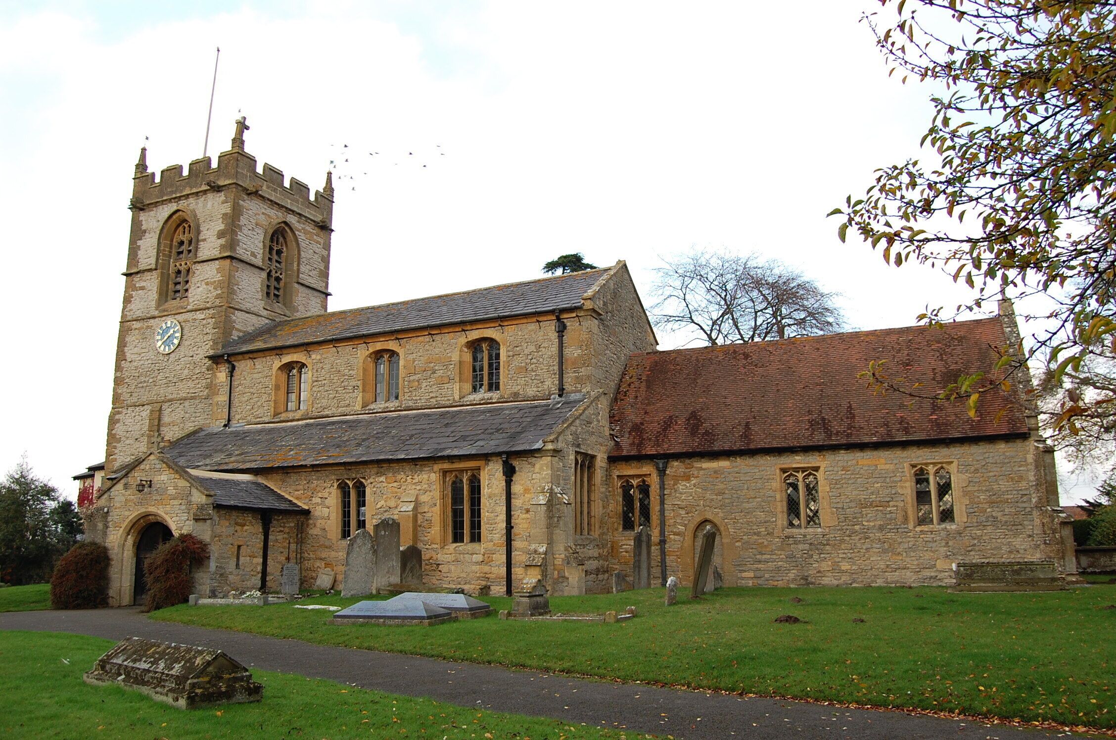 A historic stone church with a clock tower and a cemetery.