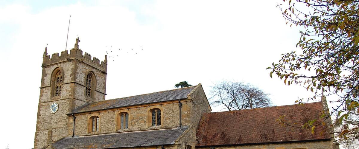 A historic stone church with a clock tower and a cemetery.