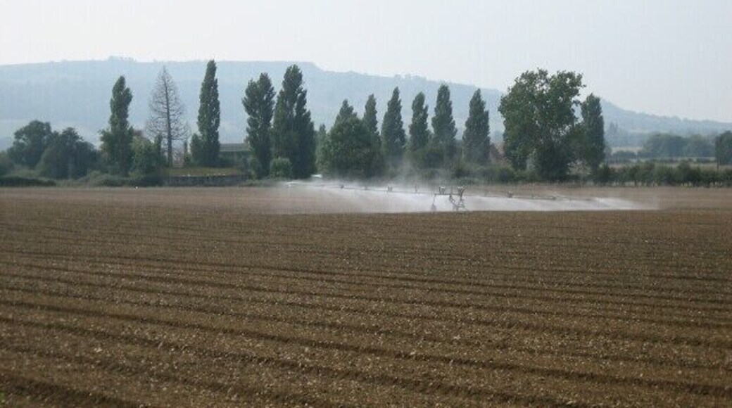 Irrigation near Cropthorne. Looking south-west from the Pershore - Evesham road towards Bredon Hill. Most of the square is given over to farming with a small industrial works dealing in caterpillar tracks.