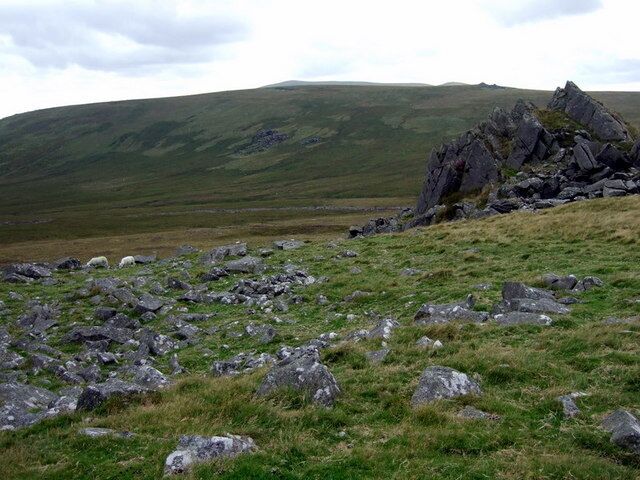 Rhestr Gerrig from Carn Menyn Looking westward from Carn Menyn the thin grey line in the middle distance is called Rhestr Gerrig, the stone row or River of Stones, a moraine left by a shrinking glacier, now partially buried in peat and overgrown by heather. The sweep of moorland beyond is Cors Tewgyll.