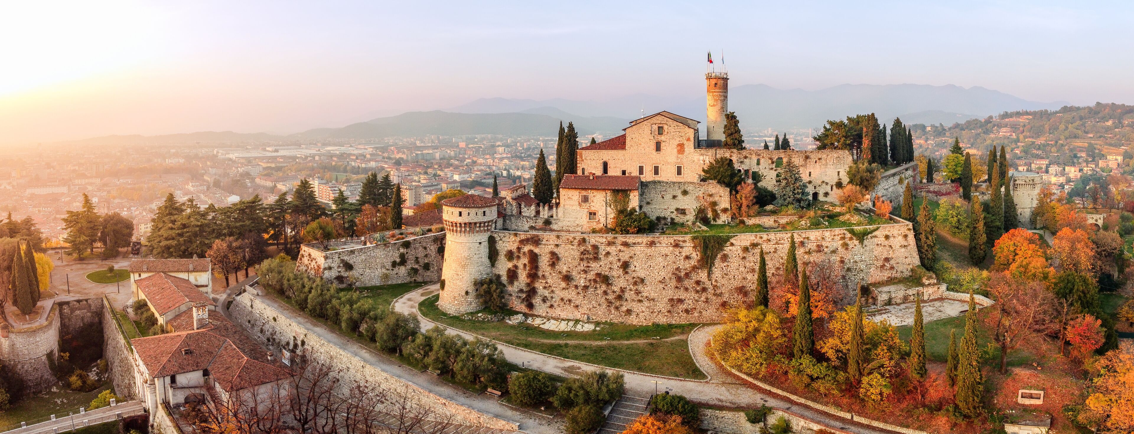 Panoramic drone view on medieval fortress Castello di Brescia, via del Castello and historical building complex on Cidneon mountain slope at autumn. Brescia, Lombardy, Northern Italy