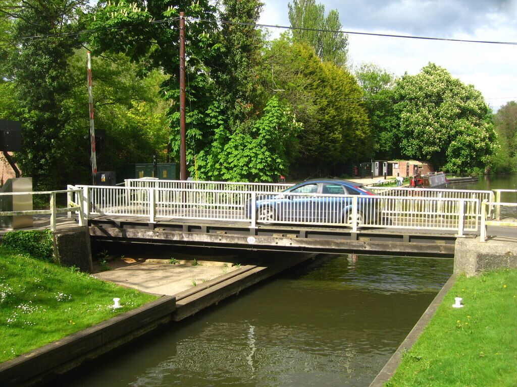A narrow canal with a pedestrian bridge and a car crossing.
