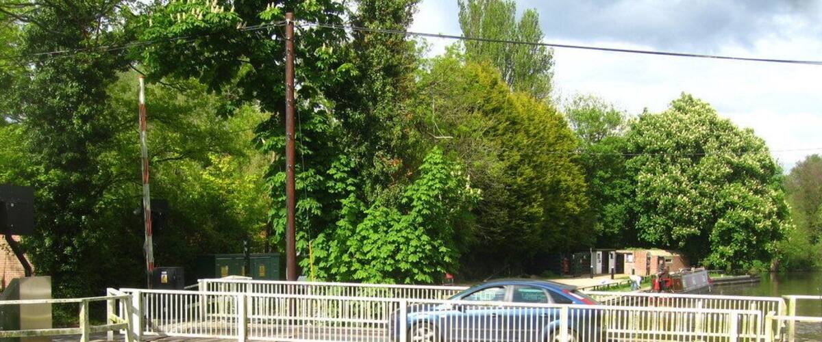 A narrow canal with a pedestrian bridge and a car crossing.