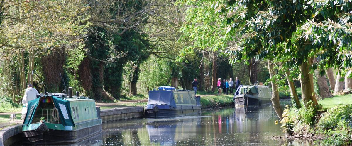 Narrow waterway with boats, trees, and a path.