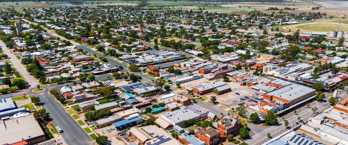 An aerial view of a town with a mix of residential and commercial buildings, roads, and green spaces.