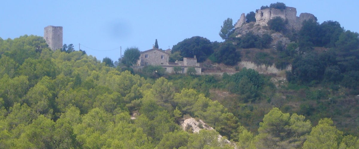 Turó del Castell de Miralles. Una torre de l'antic poble es veu a l'esquerra de la imatge, mentre que el recinte superior del castell queda a la dreta.