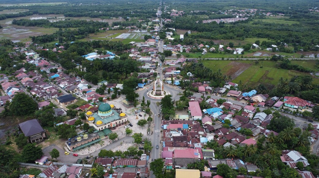 Rantau, Indonesia, 20 Desember 2024, Aerial view of city square roundabout with traffic activity and dense settlements around the roundabout
