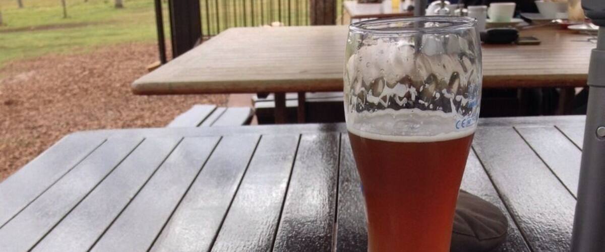 A meal of fish and chips with a side salad and a glass of beer on a wooden table.