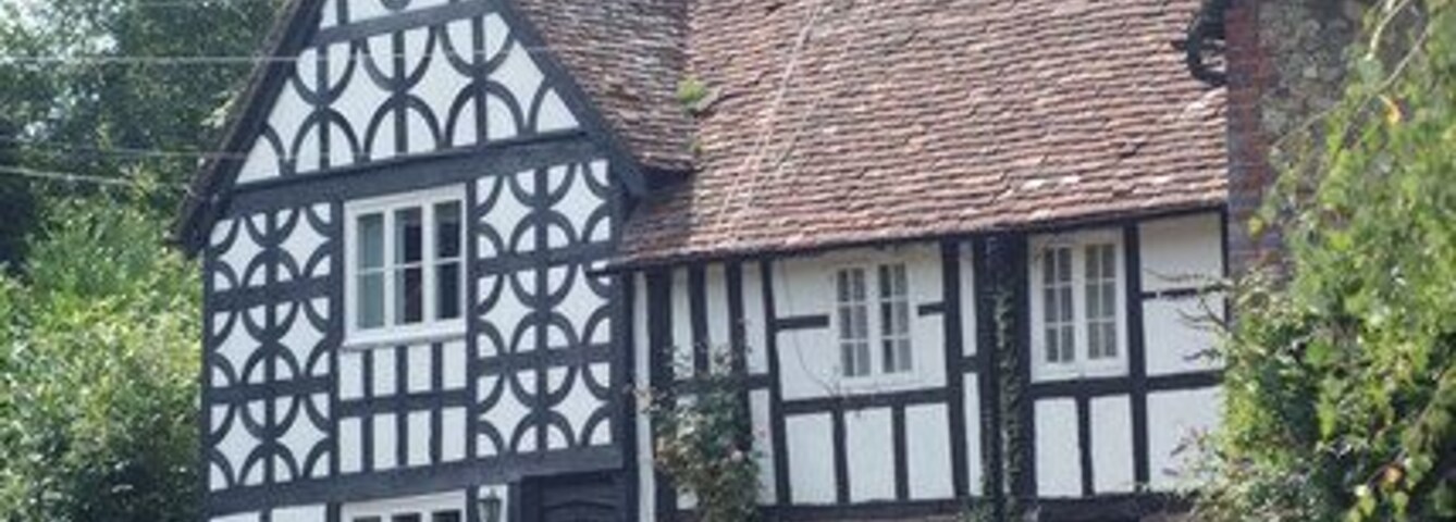 Uma casa em estilo Tudor com estrutura de madeira aparente e telhado inclinado, e chaminé.