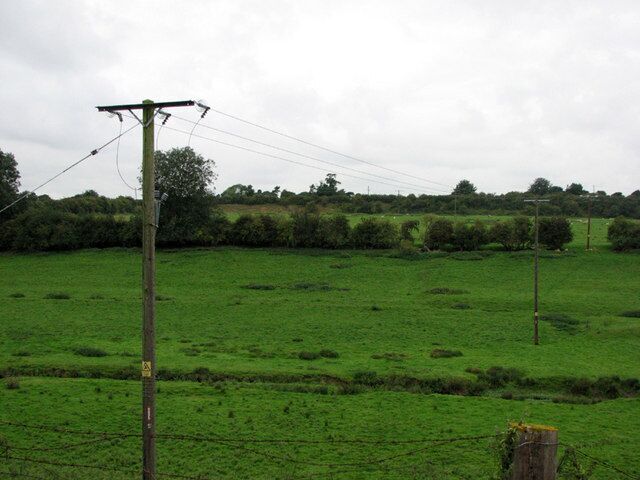 Colsterworth: view across the Witham The infant Witham is in the foreground. Old Post Lane runs north to south along the horizon, above the level of the fields beyond the hedge in the middle of the picture, which were from 1920-33 the rail-served Colsterworth No 1 Quarry. The reddish quarry face - shown on the OS Map - can be seen to the right of the telegraph pole; further to the right it is overgrown by bushes. See other photos nearby for more on the ironstone quarries and railways around Colsterworth and Woolsthorpe.