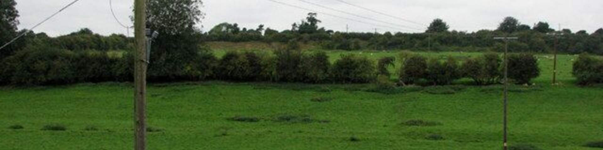 Paisaje rural con un poste de electricidad y líneas de alta tensión.