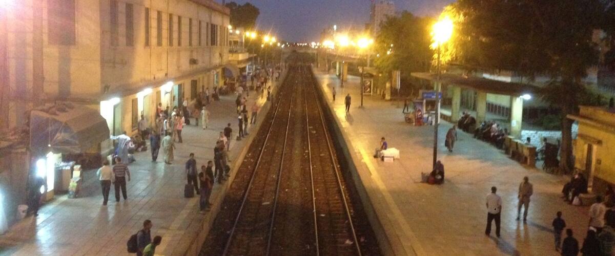 A train station platform at night with people waiting and walking.