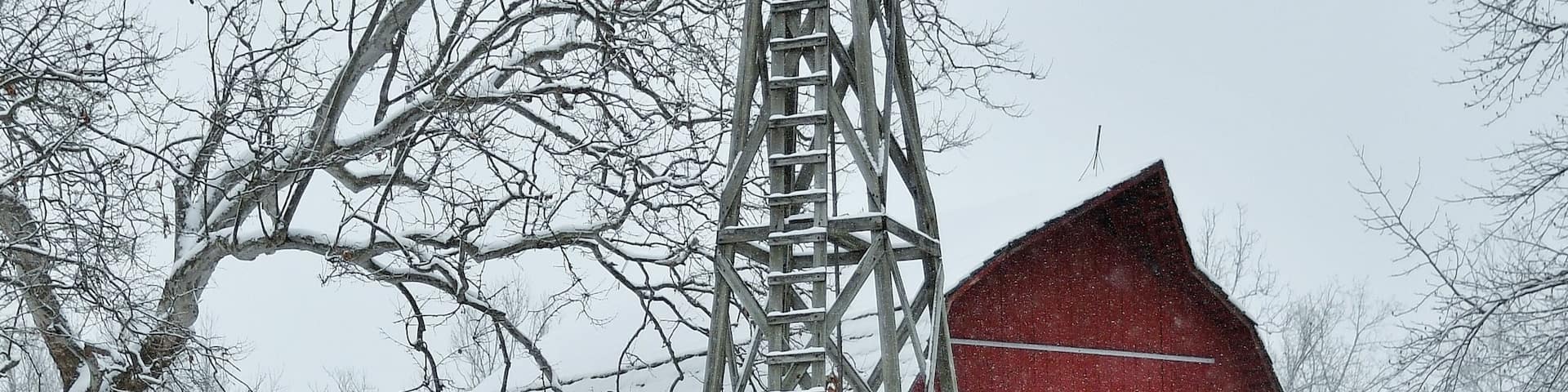 Winter, snow covered, landscape scene with a windmill and red barn in the background