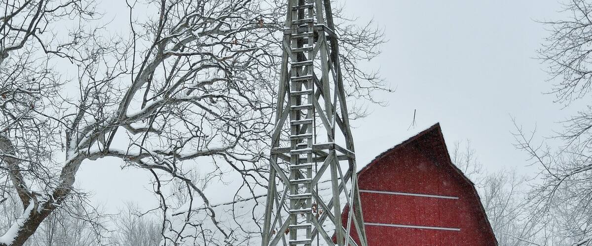 A windmill, a red barn, and snow-covered trees.