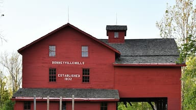 Um celeiro vermelho com a inscrição "Bonneville Mills" e "Fundado em 1832" refletido em um lago.