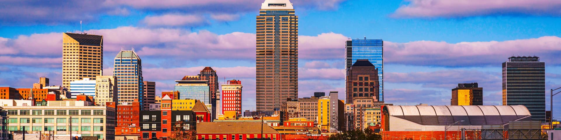 A city skyline with various buildings, including a prominent tall skyscraper and several other high-rise structures.