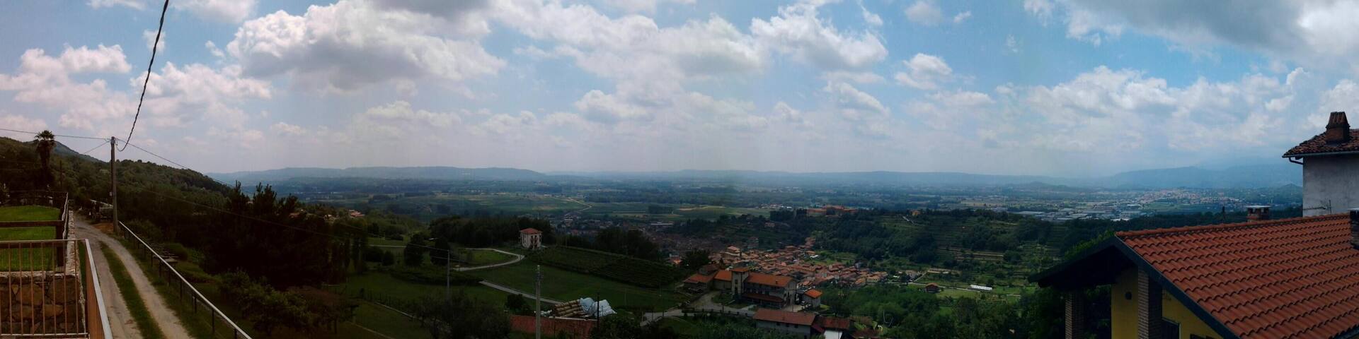 A panoramic view of a valley with a town, rolling hills, and a clear sky.