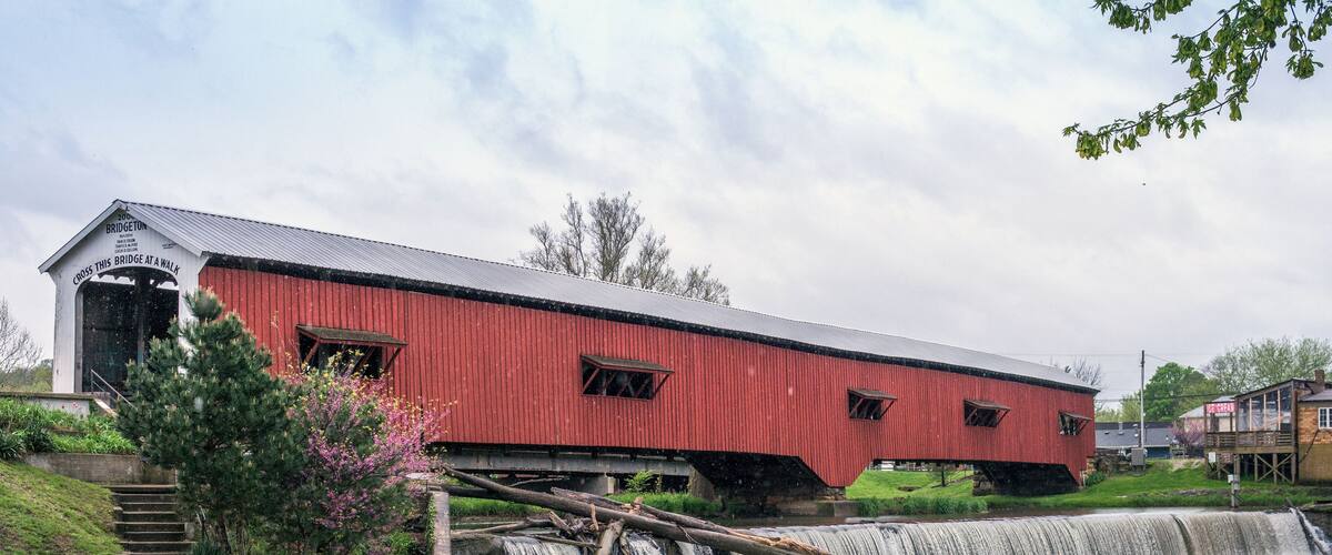 A red covered bridge over a waterfall.
