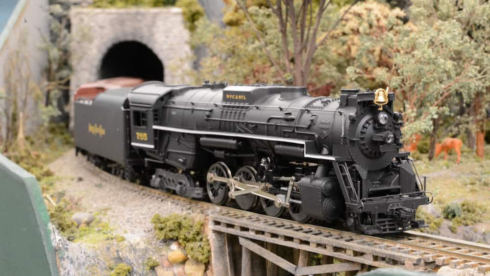 A model train on tracks with a tunnel in the background.