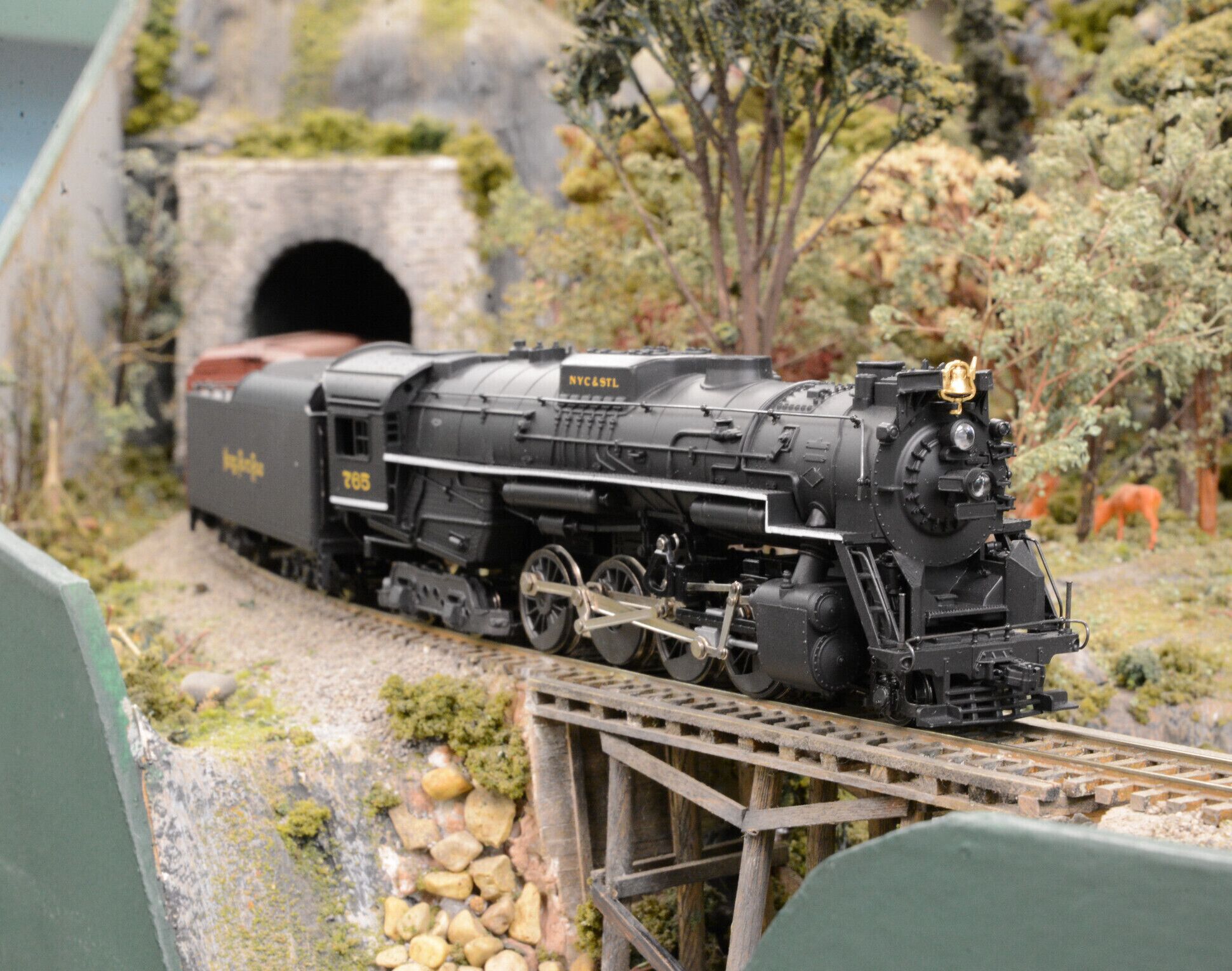 A model train on tracks with a tunnel in the background.