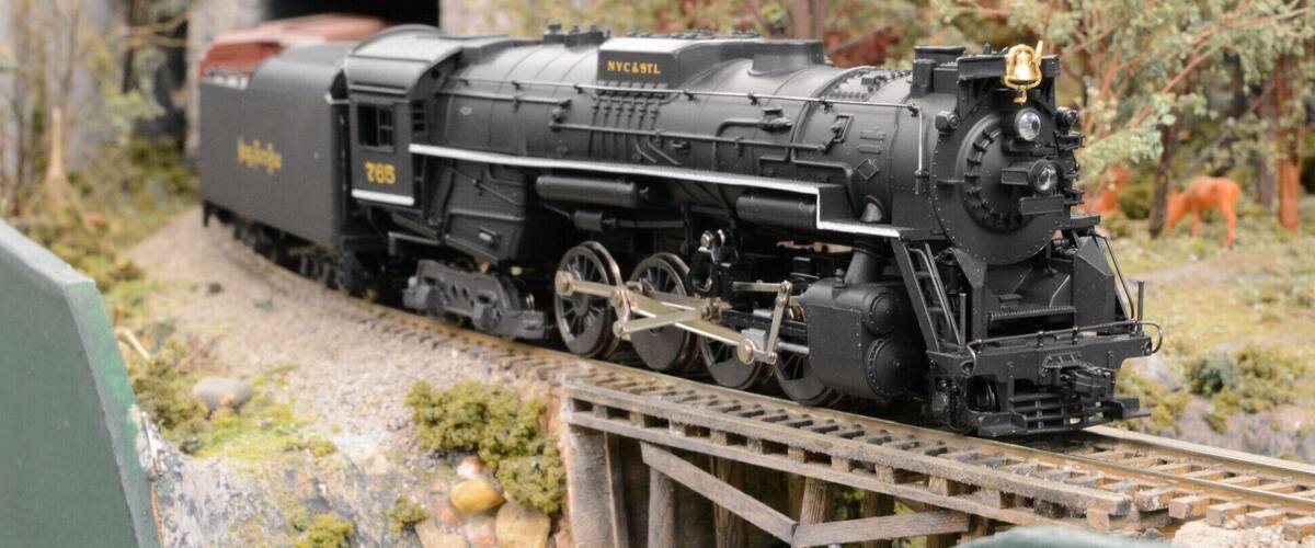 A model train on tracks with a tunnel in the background.