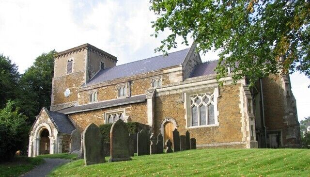 A historic church with a prominent tower, arched windows, and a surrounding graveyard.