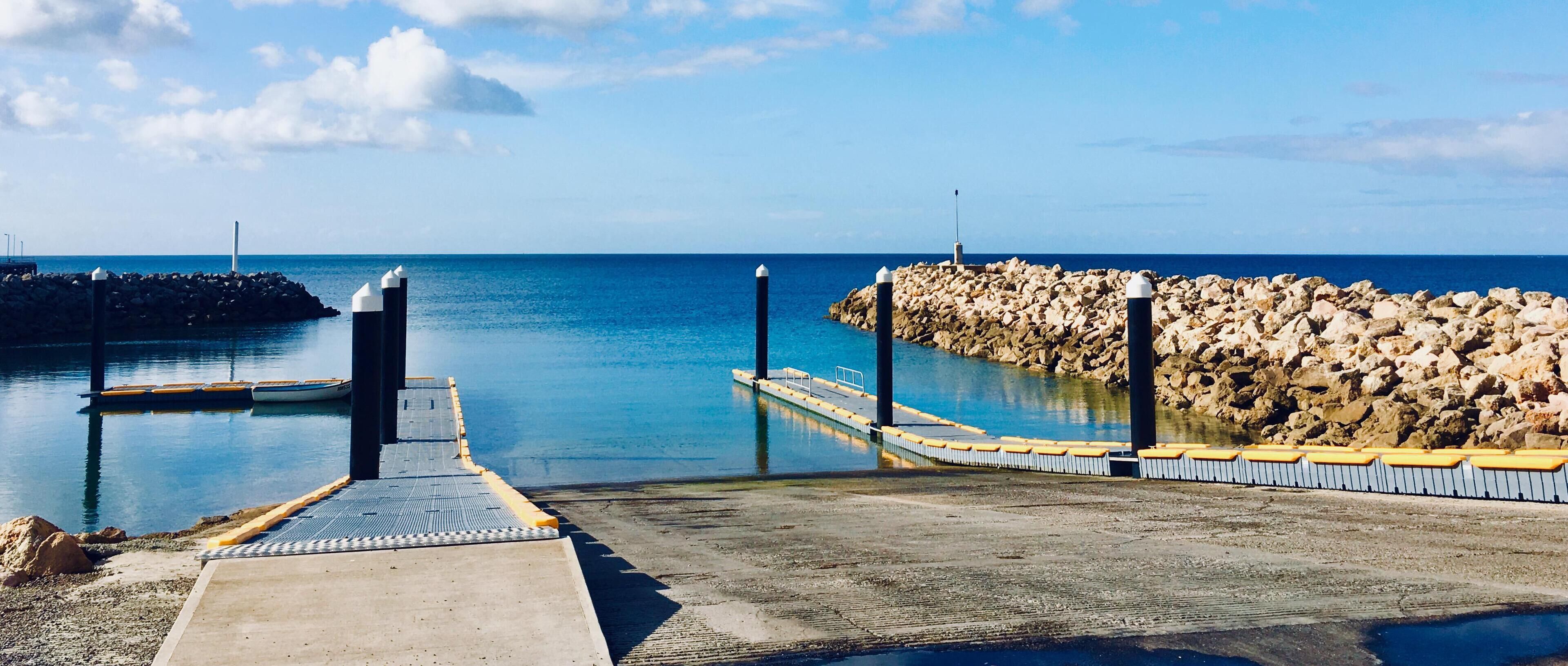 A pier extending into calm waters with a rocky breakwater on the right.