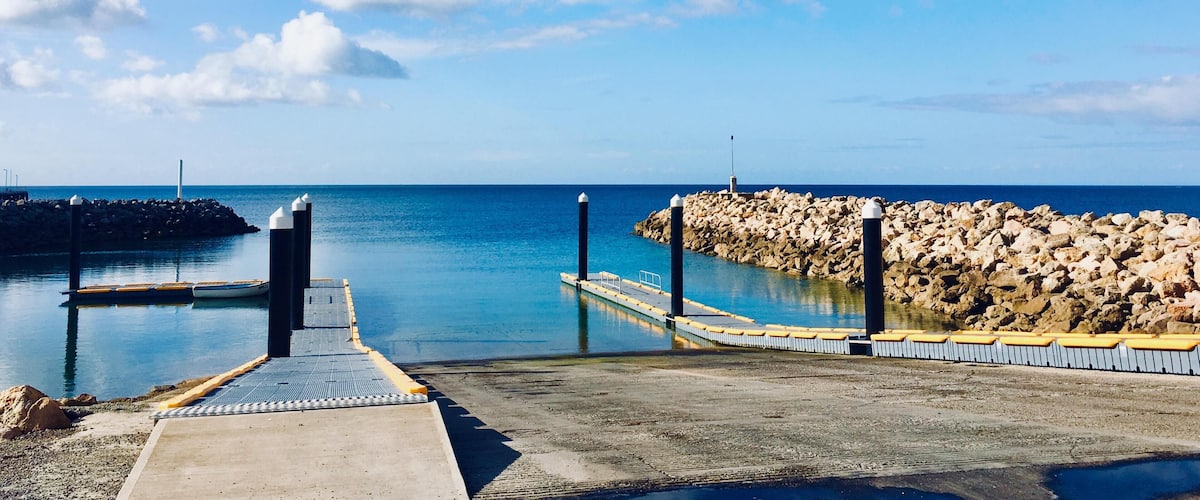 A pier extending into calm waters with a rocky breakwater on the right.