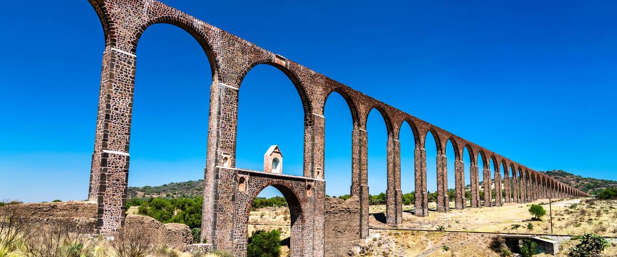 A long stone viaduct with multiple arches, set against a clear blue sky.
