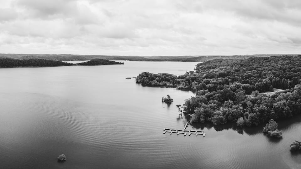 A large body of water with a forested island and a dock.