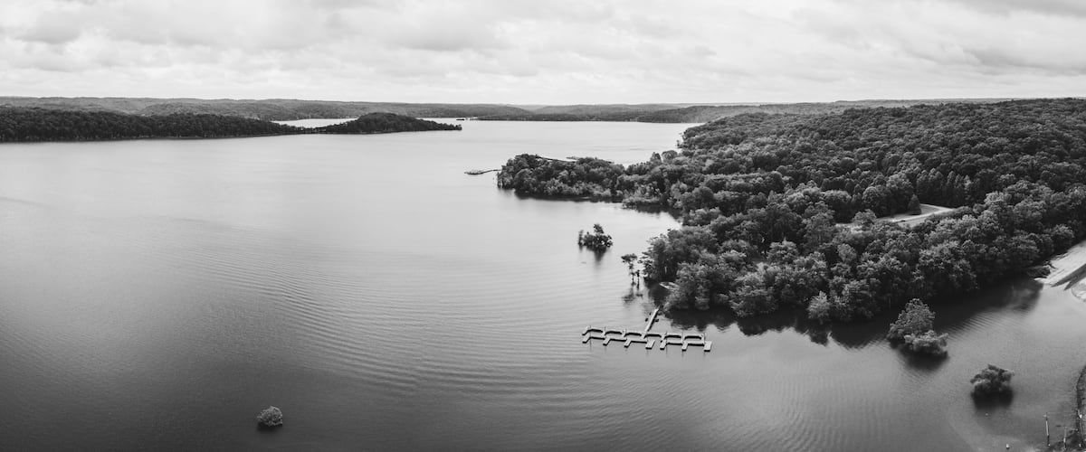 A large body of water with a forested island and a dock.
