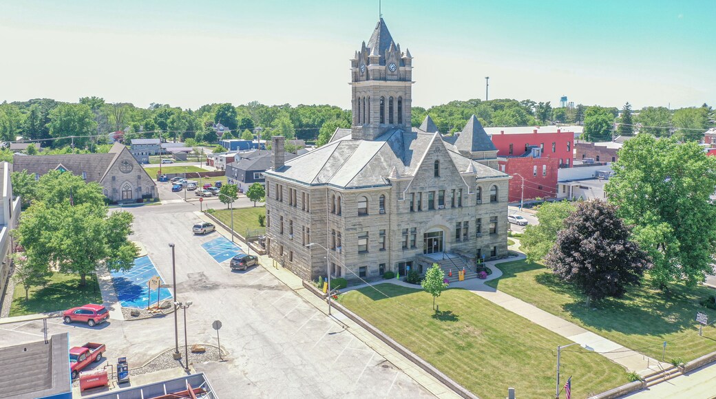 A large stone building with a clock tower, surrounded by a parking lot and trees.