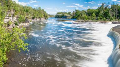 The blurred water of Ranney Falls in Ferris Provincial Park near Campbellford, Ontario is seen in the foreground, with the suspension bridge in the background.