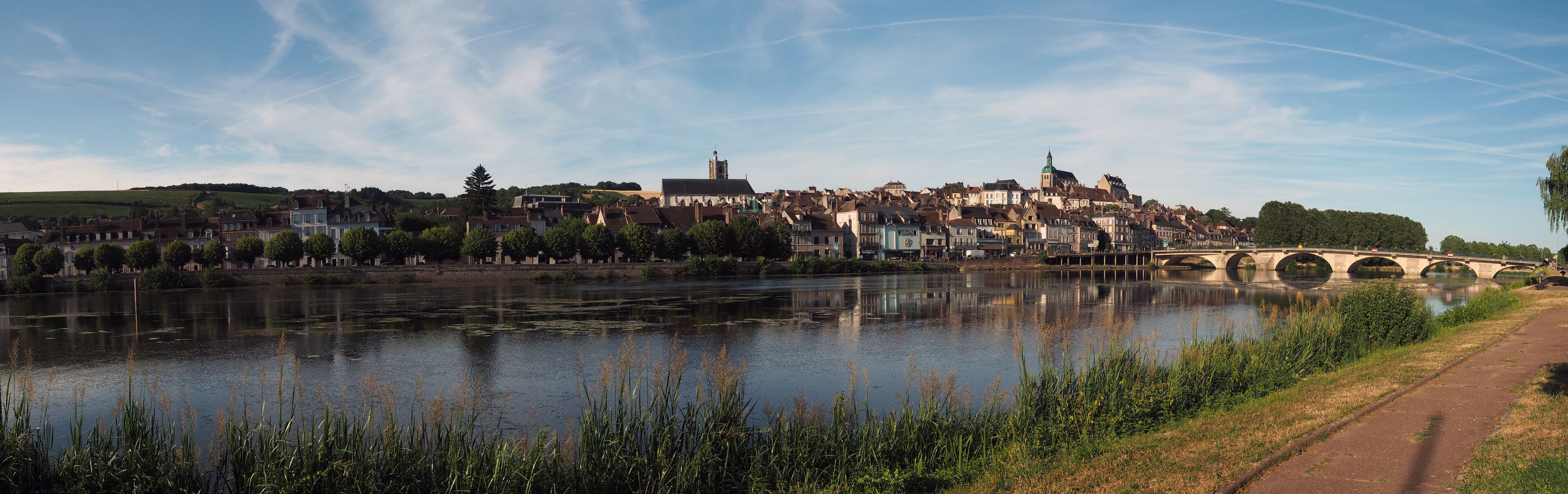 A riverside town with a bridge, historic buildings, and a church tower.